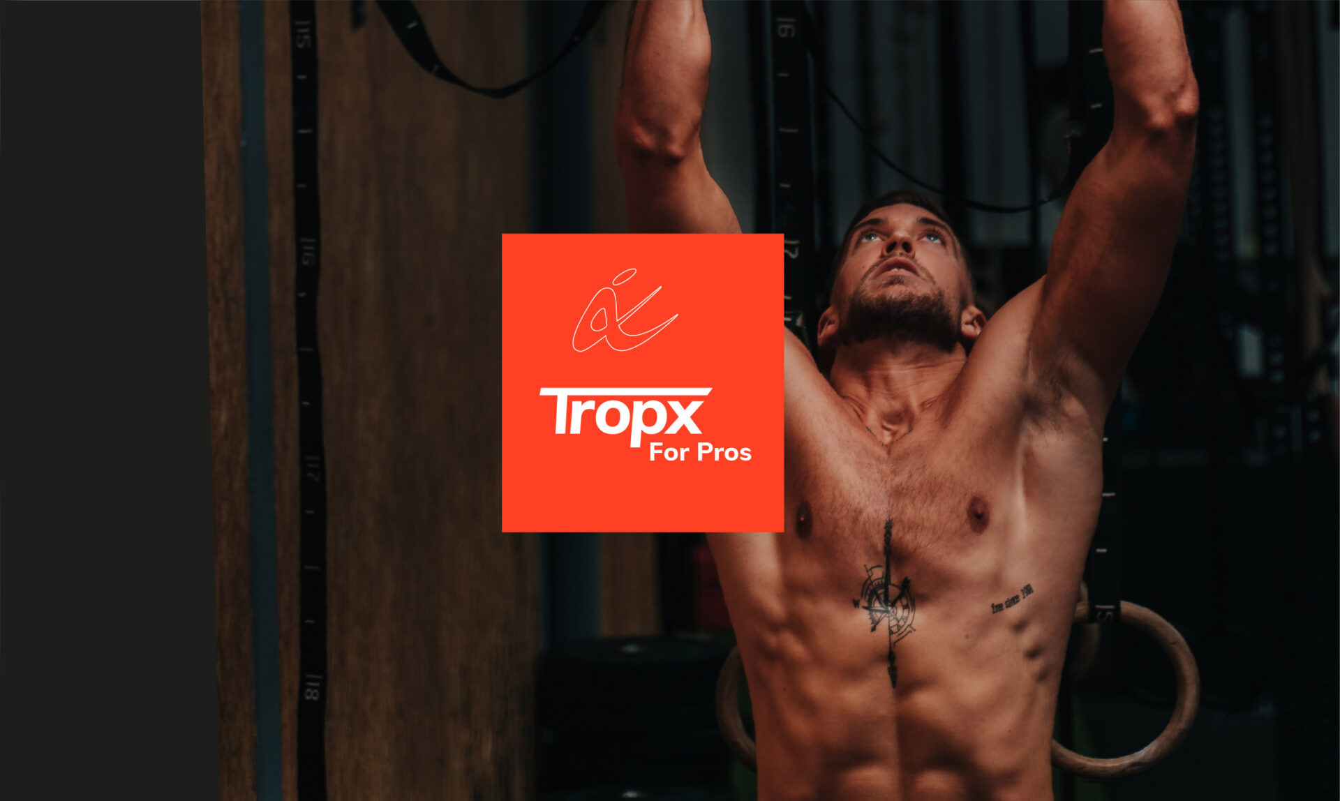 איש מתאמן בחדר כושר מבצע תרגיל כוח עם טבעות אימון, באור טוב וממוקד.