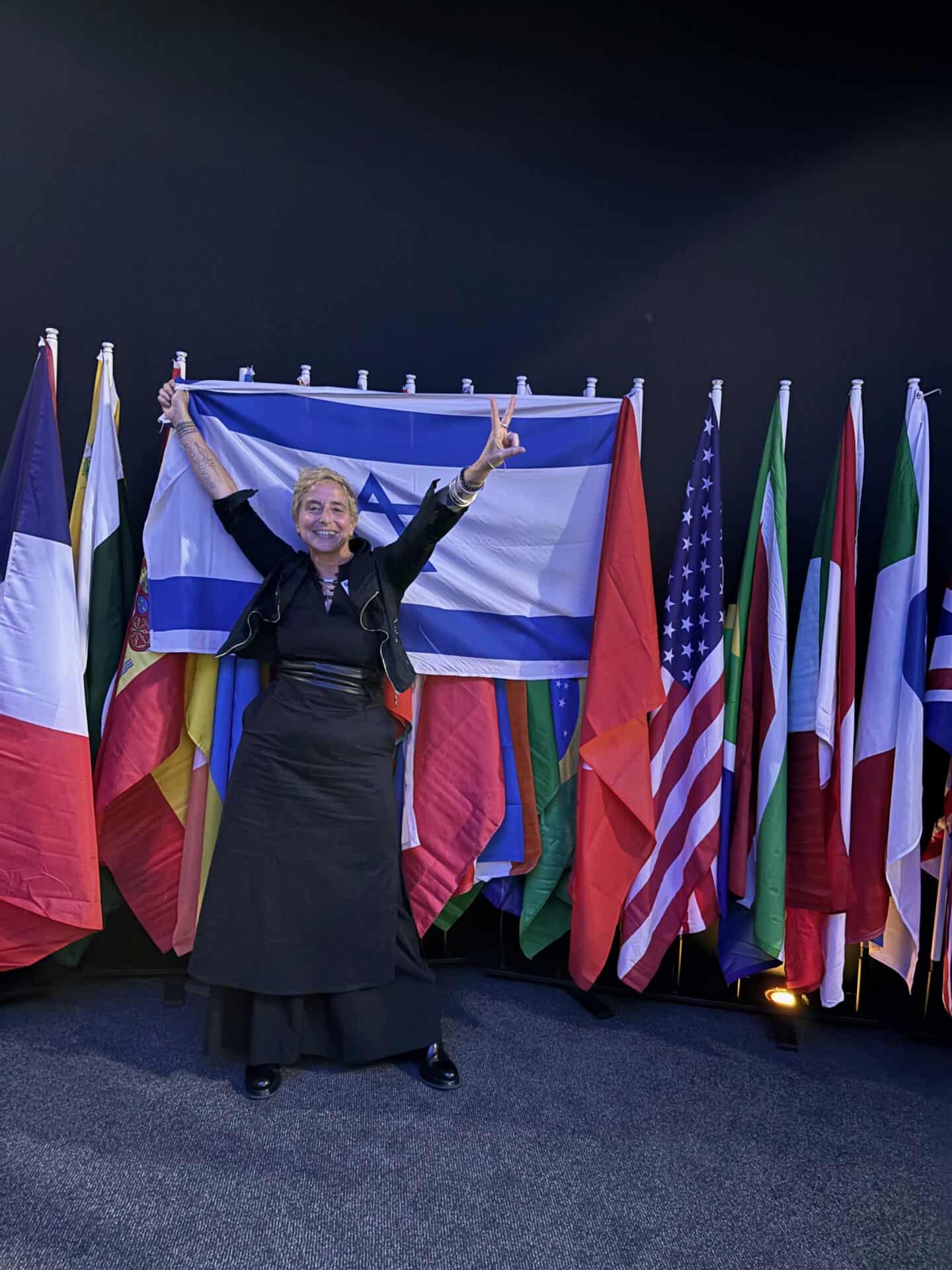 אישה מחזיקה דגל ישראל עם דגלי מדינות נוספות ברקע, זוכה בפרס עיצוב אריזות.