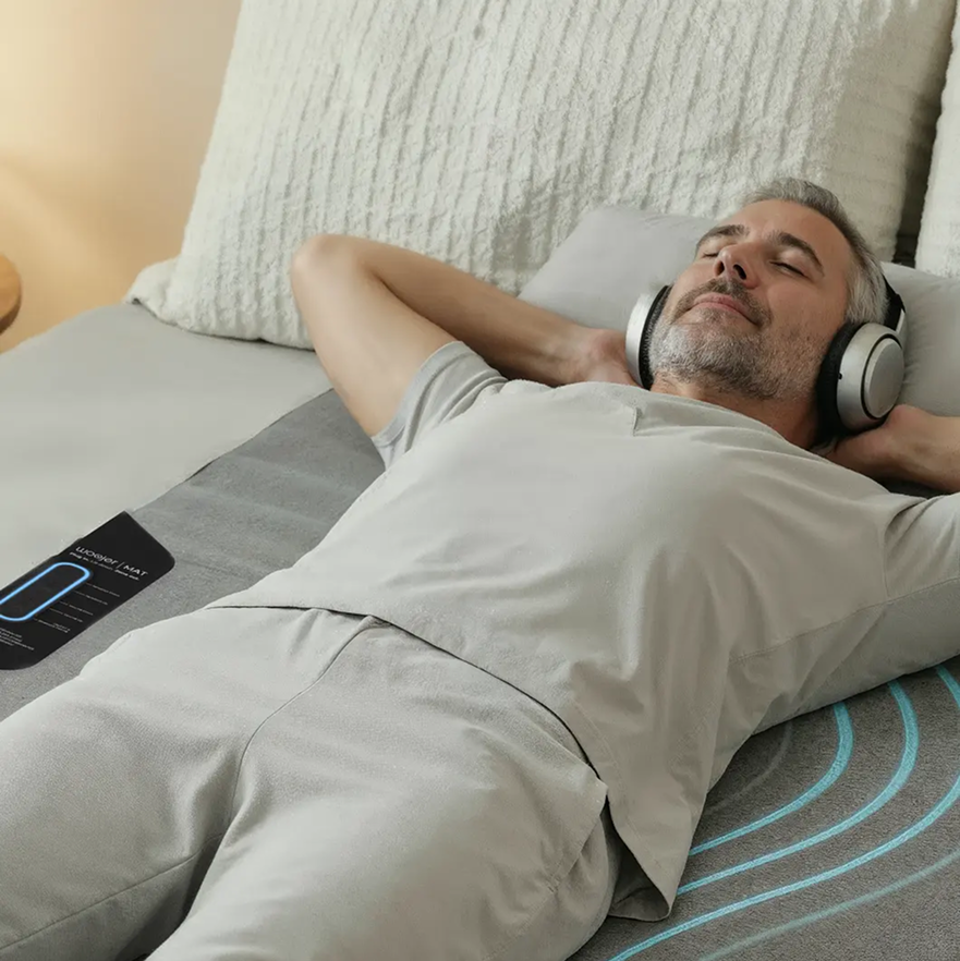 גבר נהנה מחוויית שמע עם אוזניות Woojer MAT בשינה נוחה.